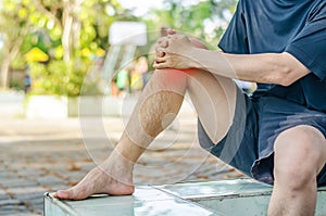 Young sport man with strong athletic legs holding knee