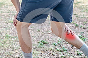 Young sport man with strong athletic legs holding knee