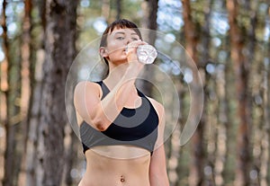 Young Sport Woman Drinking Water During Running in Beautiful Wild Pine Forest. Active Lifestyle Concept.