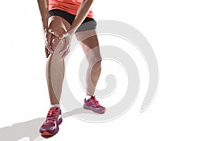 Young sport woman with strong athletic legs holding knee with hands in pain suffering ligament injury