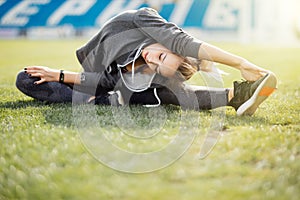 Young sport woman in white stretching in park on the grass