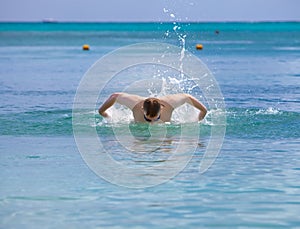 Young sporting man swims in the sea
