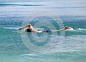 Young sporting man swims in sea