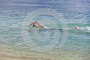 Young sporting man swims in the sea