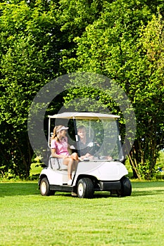 Young sportive couple with golf cart on a course