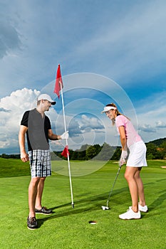 Young sportive couple playing golf on a course