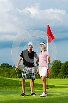 Young sportive couple playing golf on a course