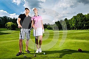 Young sportive couple playing golf on a course