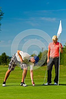 Young sportive couple playing golf on a course