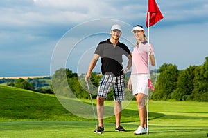 Young sportive couple playing golf on a course photo