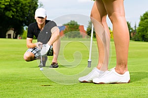 Young sportive couple playing golf on a course photo