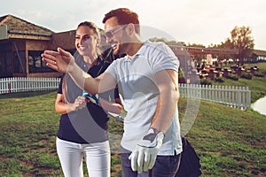 Young sportive couple playing golf on a golf course.