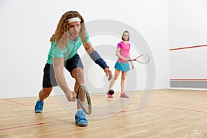 Young sportive couple practicing squash at sport club court