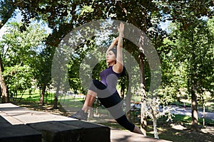 Young sportive girl doing sports exercises outdoors in the park
