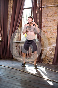 Young sportive man boxing with dumbbells.