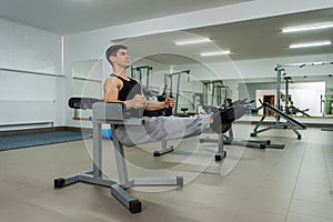 Young and sportive man making stretching exercises in gym