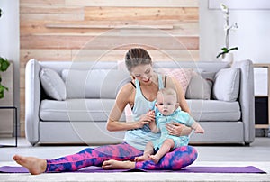 Young sportive woman doing exercise with her son at home.