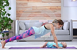 Young sportive woman doing exercise with her son at home