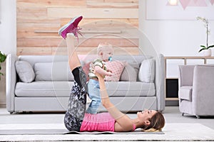 Young sportive woman doing exercise with her son at home