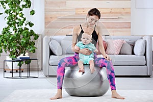 Young sportive woman doing exercise with her son at home.