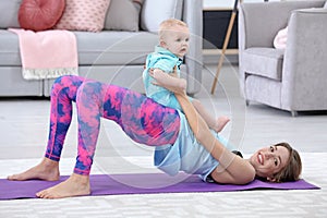 Young sportive woman doing exercise with her son at home.