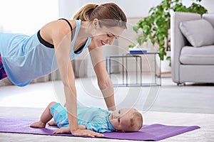 Young sportive woman doing exercise with her son at home.