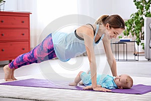 Young sportive woman doing exercise with her son at home.