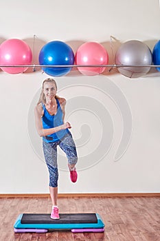 Young sportive woman exercising in gym using step platform