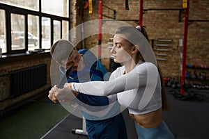 Young sportive woman exercising with knife weapon with trainer