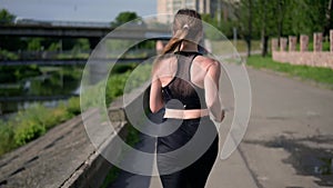 Young sportive woman jogging on the city street. Back view. Fitness, sport and healthy lifestyle concept