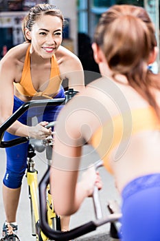 Young sportive woman pedaling during indoor gym cycling