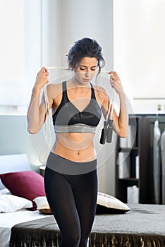 Young sportive woman with skipping rope at home