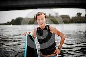 Young sportive woman stands with surf board on blurred background