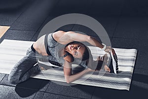 young sportive woman stretching on mat before training