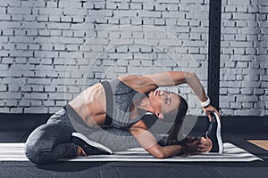 young sportive woman stretching on mat before training