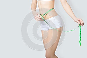 Young sports a beautiful slim woman measuring perfect shape nice hips, the concept of a healthy lifestyle on a white background