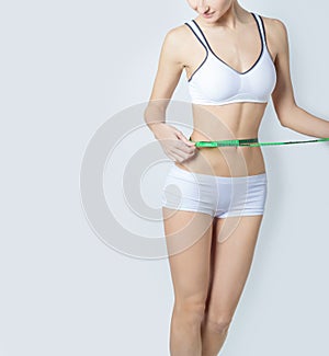 Young sports a beautiful slim woman measuring perfect shape nice hips, the concept of a healthy lifestyle on a white background