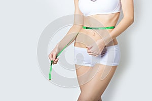 Young sports a beautiful slim woman measuring perfect shape nice hips, the concept of a healthy lifestyle on a white background