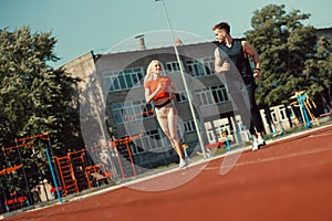 Young sports couple running in the stadium on the running track