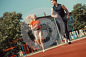 Young sports couple running in the stadium on the running track