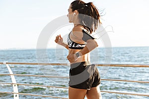 Young sports fitness woman running at the beach outdoors