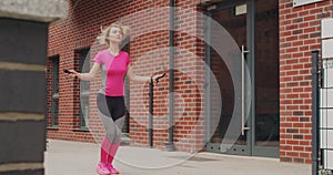 Young sports girl is jumping with a skipping rope outdoors in the city.