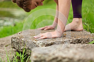 A young sports girl practices yoga in a quiet location on the river bank in summer, in a yoga asana pose. Meditation and oneness