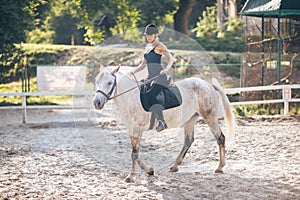 A young sports girl is riding a horse