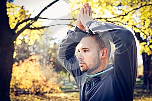 Young sports man doing yoga. Autumn season.