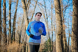 Young Sports Man Running in the Park in Cold Sunny Autumn Morning. Healthy Lifestyle and Sport Concept.