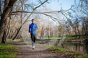 Young Sports Man Running in the Park in Cold Sunny Autumn Morning. Healthy Lifestyle and Sport Concept.