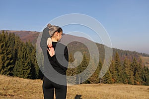 Young sports woman doing yoga exercise on the mountains and sky background in the autumn