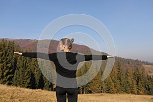 Young sports woman doing yoga exercise on the mountains and sky background in the autumn