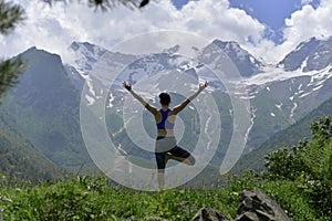 Young sports woman doing yoga on the green grass in the summer.